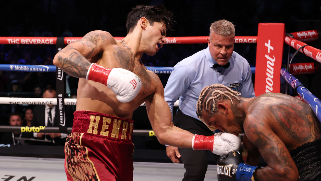 Boxer in red trunks lands a punch as the referee watches in the ring